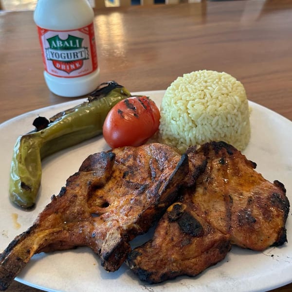 Grilled lamb chops with rice, roasted pepper, tomato, and a bottle of Abali yogurt drink.
